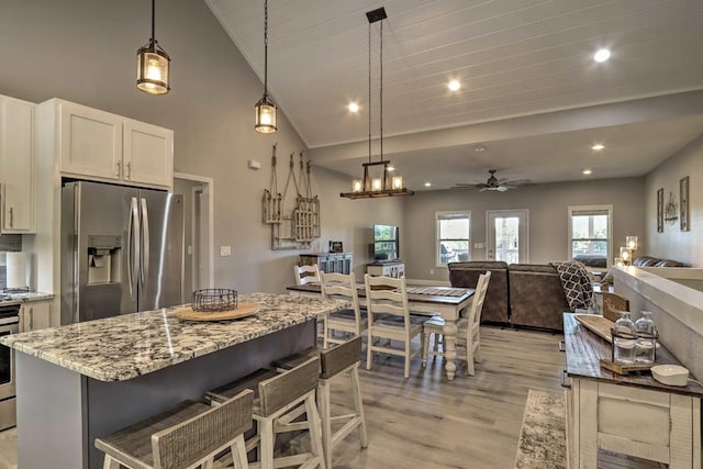 kitchen featuring light stone countertops, white cabinetry, stainless steel appliances, and decorative light fixtures