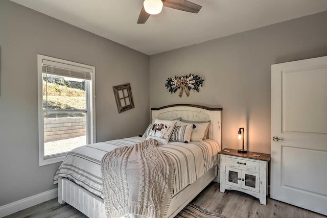 bedroom featuring multiple windows, baseboards, and wood finished floors