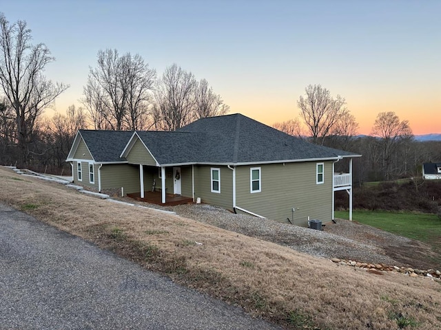 view of front of property featuring a shingled roof, covered porch, and central AC