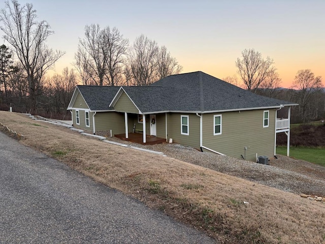 view of front of house featuring a shingled roof, a front yard, cooling unit, and a porch