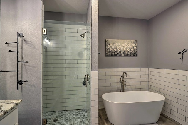 bathroom featuring hardwood / wood-style floors, a textured ceiling, vanity, independent shower and bath, and tile walls