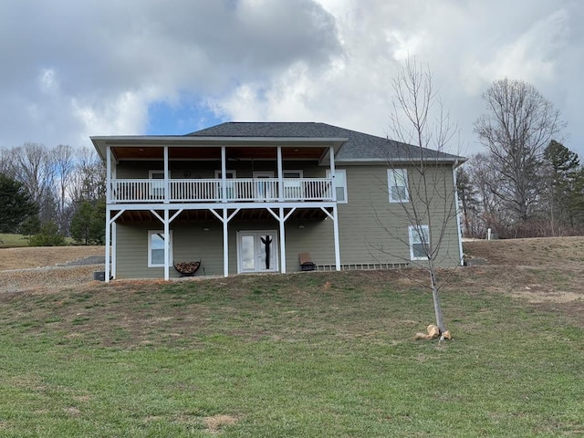 back of property with a yard, roof with shingles, and a wooden deck