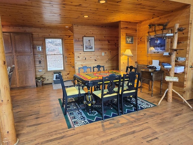 dining area with wood-type flooring, wooden ceiling, and wooden walls