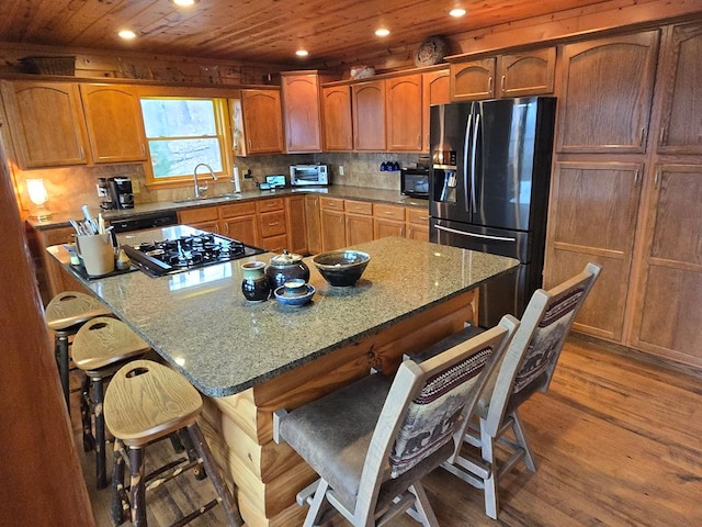 kitchen with sink, a kitchen breakfast bar, a center island, light hardwood / wood-style floors, and black appliances