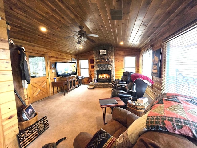 carpeted living room featuring ceiling fan, wooden walls, a fireplace, vaulted ceiling, and wooden ceiling