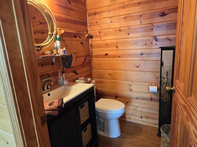 bathroom with vanity, hardwood / wood-style flooring, toilet, and wood walls