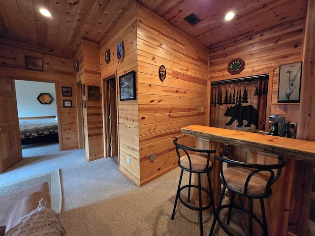 bar featuring wooden ceiling, light colored carpet, wooden counters, and wood walls