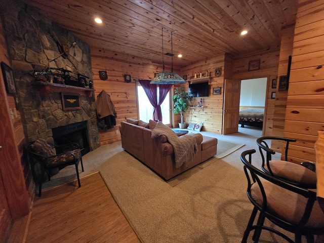 carpeted living room featuring a stone fireplace, wooden walls, and wood ceiling