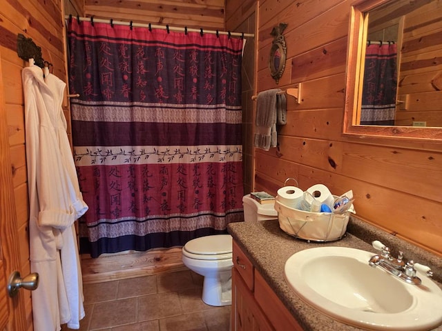 bathroom with vanity, toilet, tile patterned flooring, and wood walls