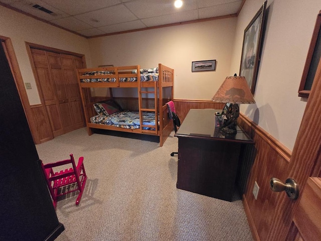 bedroom with a closet, light carpet, and wood walls