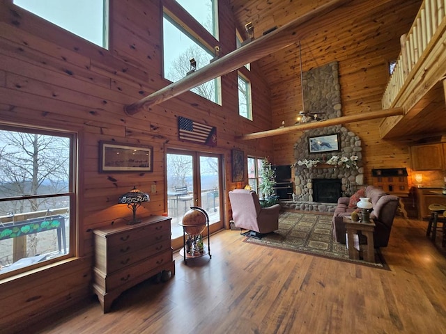 living room with a fireplace, a towering ceiling, plenty of natural light, and wood-type flooring