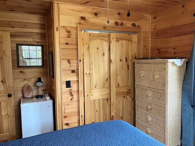 bedroom featuring refrigerator, wooden ceiling, and wood walls