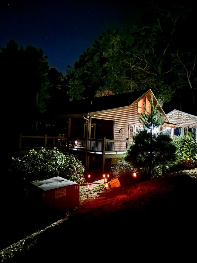 back of house at night featuring a deck