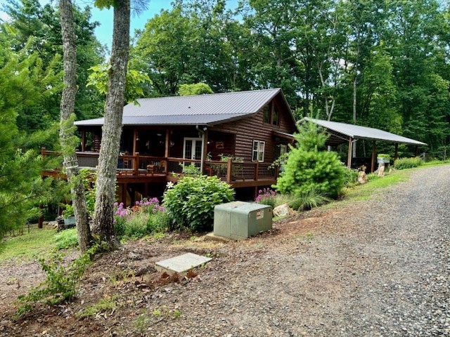 rear view of house with a deck, metal roof, and gravel driveway