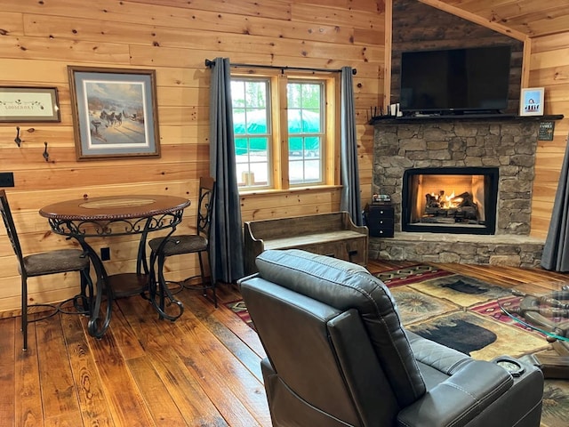 living room featuring hardwood / wood-style floors, wooden walls, and a fireplace