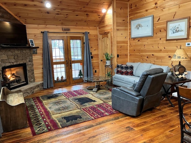 living room with a fireplace, wooden walls, french doors, wood-type flooring, and wooden ceiling