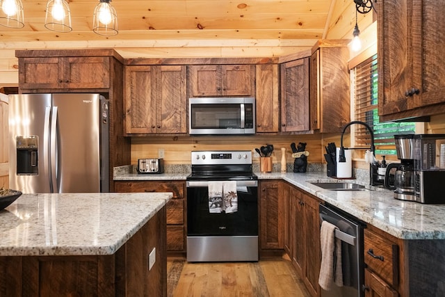 953 Lemmon Ln, Ellijay, GA 30540 - kitchen featuring appliances with stainless steel finishes, light wood-style floors, a sink, hanging light fixtures, and brown cabinetry