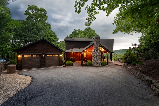 chalet / cabin with an attached garage, a shingled roof, and driveway