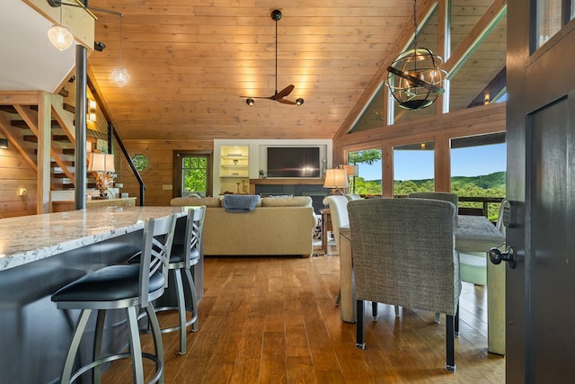 dining room with wood walls, lofted ceiling, and wood-type flooring