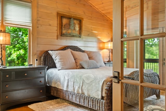 bedroom featuring lofted ceiling, wood walls, and access to exterior