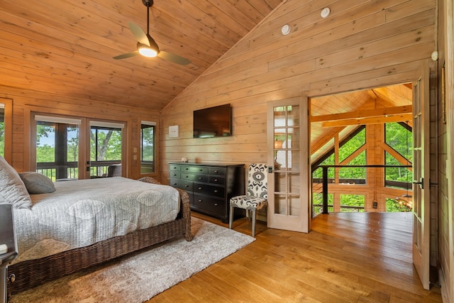 bedroom featuring wood walls, french doors, wood finished floors, vaulted ceiling, and access to outside