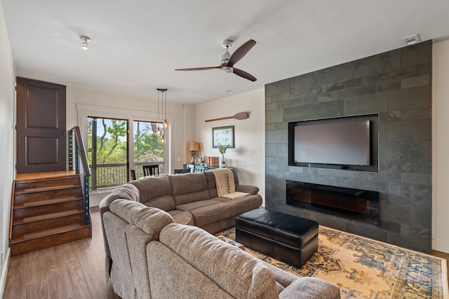 living room featuring wood finished floors, a fireplace, stairway, a ceiling fan, and baseboards