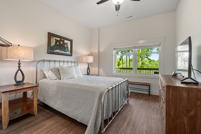 bedroom with ceiling fan, a baseboard heating unit, visible vents, and wood finished floors