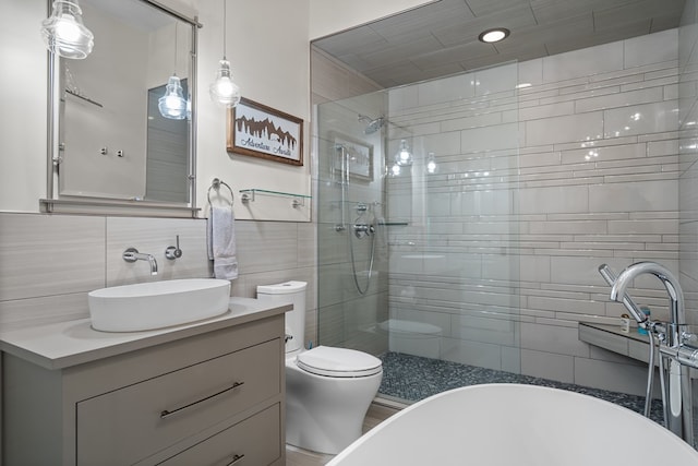 bathroom with toilet, tile walls, vanity, a soaking tub, and tiled shower