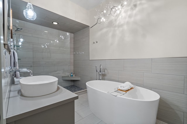 bathroom featuring tile walls, tile patterned flooring, vanity, and a freestanding tub