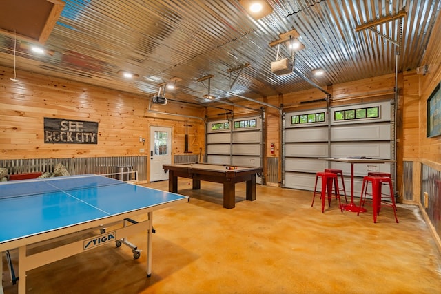 game room with wood walls, pool table, concrete floors, and a garage