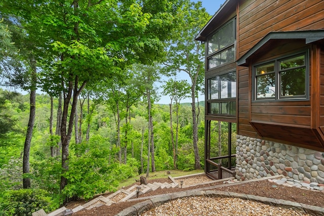 view of yard with a balcony and a wooded view