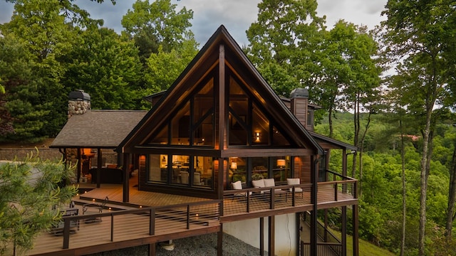 back of house featuring a chimney and a wooden deck