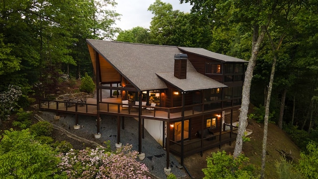 rear view of house with roof with shingles and a deck