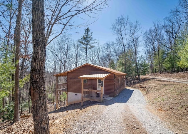 view of front of house with crawl space and gravel driveway