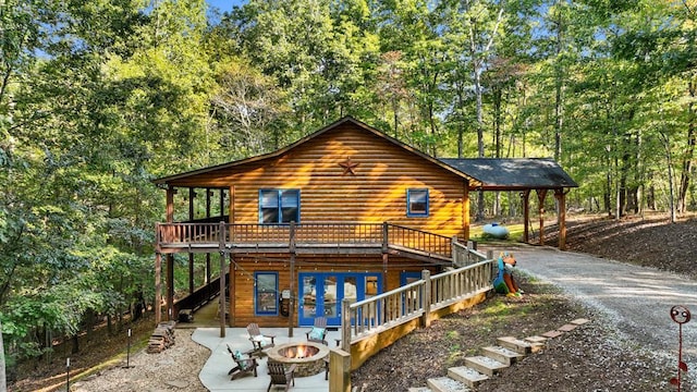 back of house with a wooden deck, a patio, and an outdoor fire pit