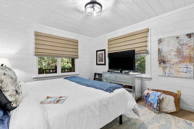 bedroom featuring wooden walls and carpet floors