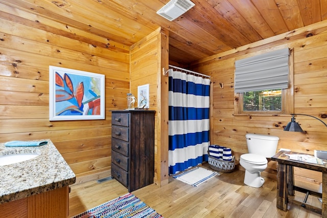 bathroom featuring vanity, wood walls, wood-type flooring, toilet, and a shower with shower curtain