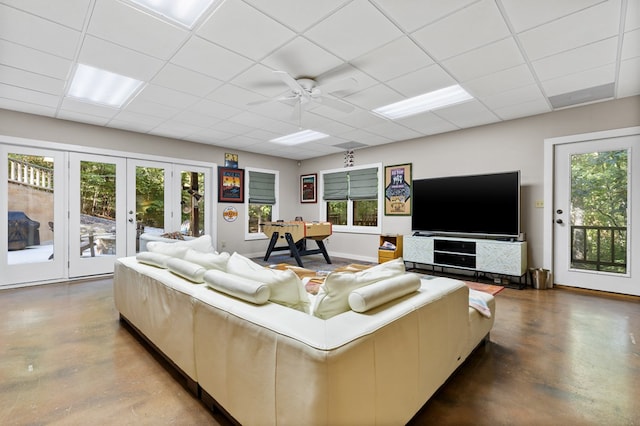 living room featuring a wealth of natural light, ceiling fan, concrete floors, and a paneled ceiling