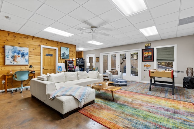 living room featuring wood walls, ceiling fan, french doors, and a wealth of natural light