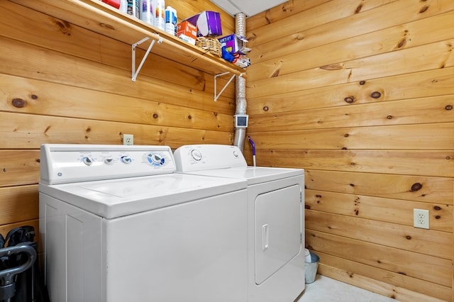 clothes washing area featuring wood walls and washing machine and dryer