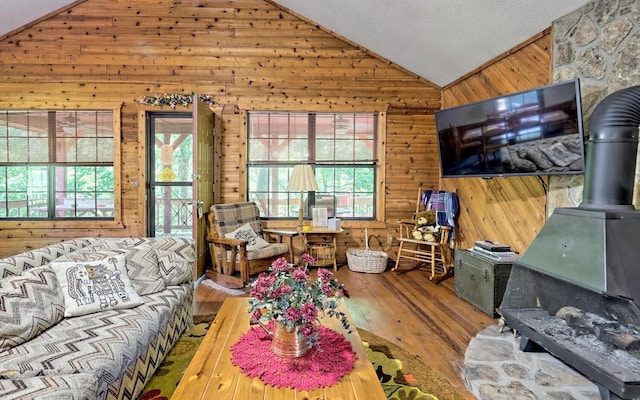 living room with a wood stove, a wealth of natural light, hardwood / wood-style floors, and lofted ceiling