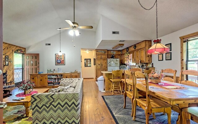 dining room with ceiling fan, light hardwood / wood-style floors, plenty of natural light, and high vaulted ceiling