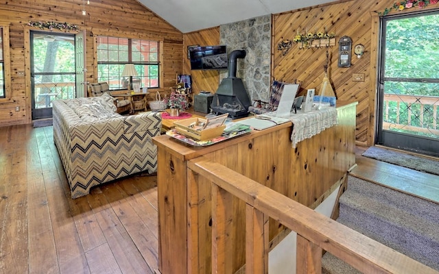 living room with vaulted ceiling, hardwood / wood-style flooring, a wood stove, and plenty of natural light