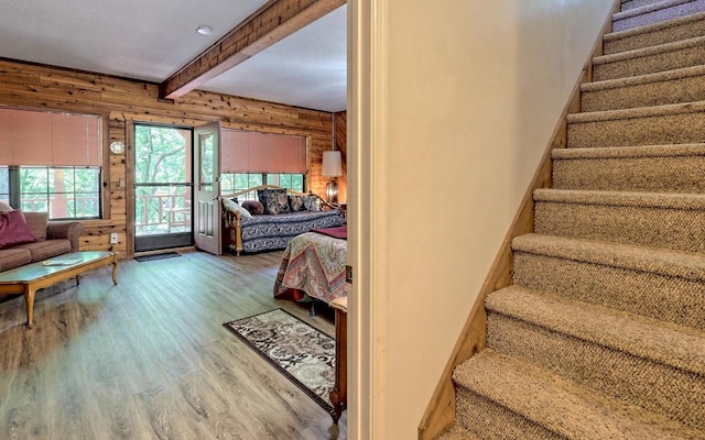 stairs featuring wood walls, beamed ceiling, and wood-type flooring