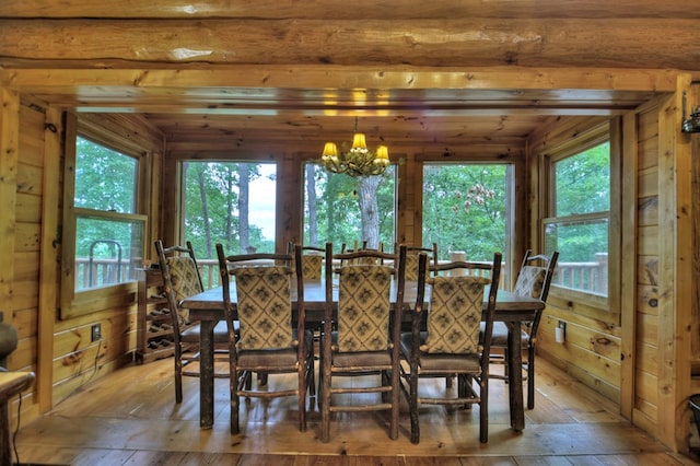 dining room featuring an inviting chandelier, hardwood / wood-style floors, and wooden walls