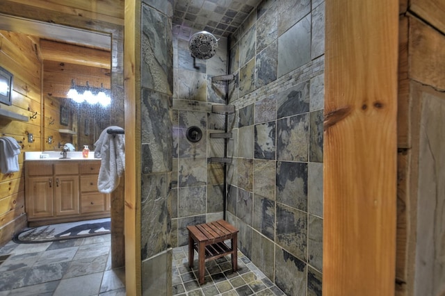 bathroom with tiled shower, vanity, and wooden walls