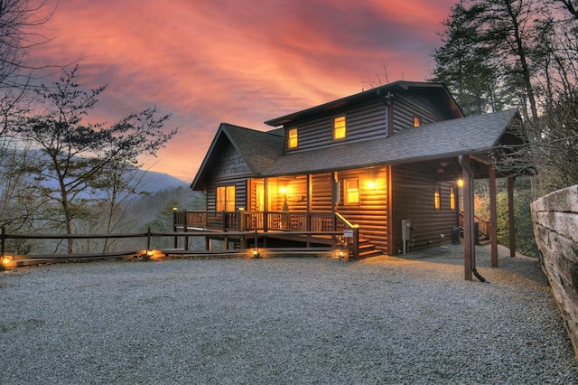 back of property at dusk featuring log veneer siding and roof with shingles