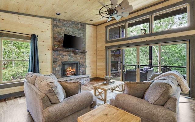 living room with light hardwood / wood-style floors, wooden ceiling, a fireplace, and wooden walls