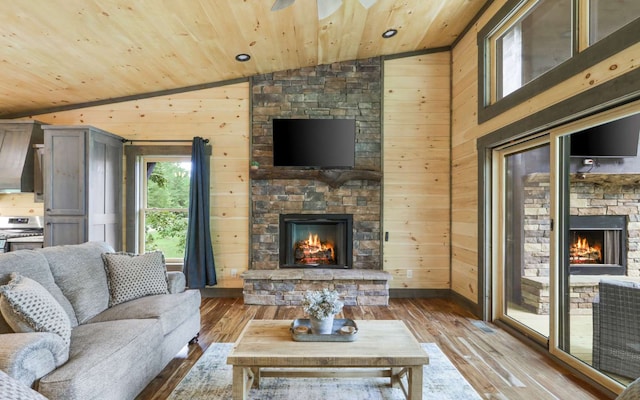 living room featuring wooden ceiling, a stone fireplace, light hardwood / wood-style flooring, wood walls, and vaulted ceiling