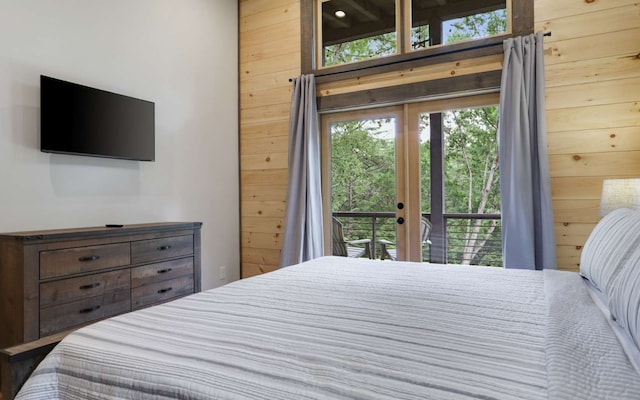 bedroom with access to exterior, french doors, and wooden walls